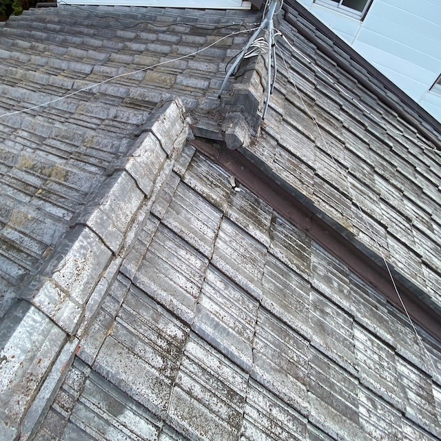 雨漏りしている棟違いのセメント屋根